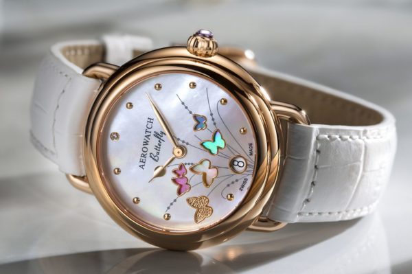 Aérowatch Collection Butterfly Montre dame, acier PVD rose, cadran nacre, 2 aiguilles rose, papillons couleurs, diamant 0.009ct à 12h, date à 6h, couronne avec pierre mauve, bracelet cuir blanc. Swiss made, garantie 2 ans.